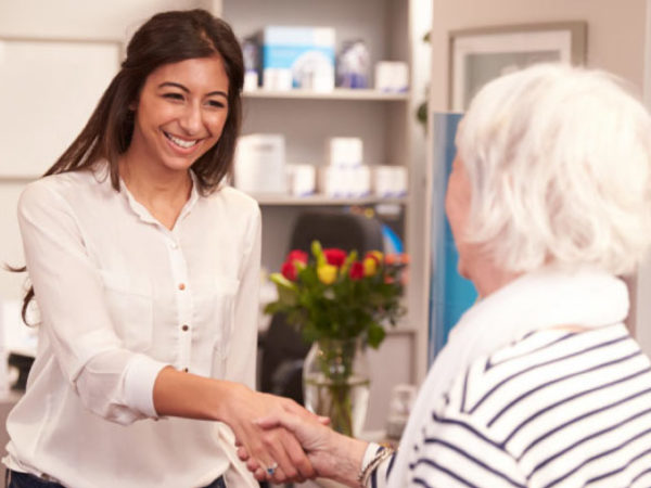 dental receptionist greets a patient with a smile and a handshake