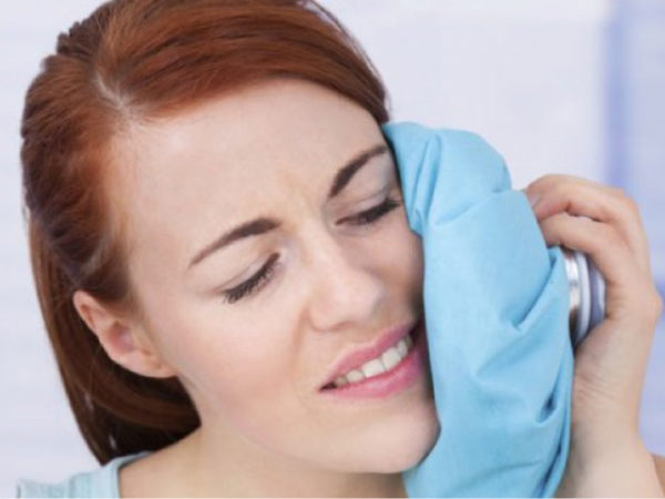 woman uses an icepack on her jaw after oral surgery