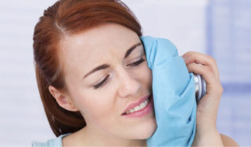 woman uses an icepack on her jaw after oral surgery